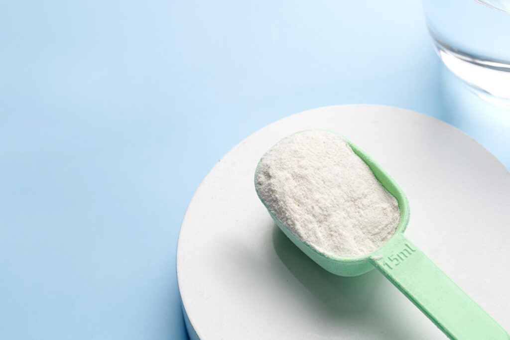 collagen protein powder with spoon glass water blue background copy space