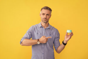Man holding a hair styling product in a jar